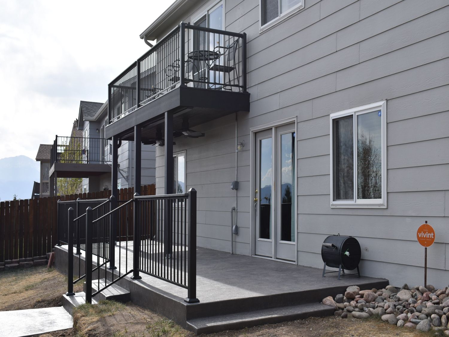 Outdoor living spaces created in Colorado Springs with an elevated composite deck featuring an under-deck drainage system with tongue and groove flat ceiling and a stamped concrete patio below