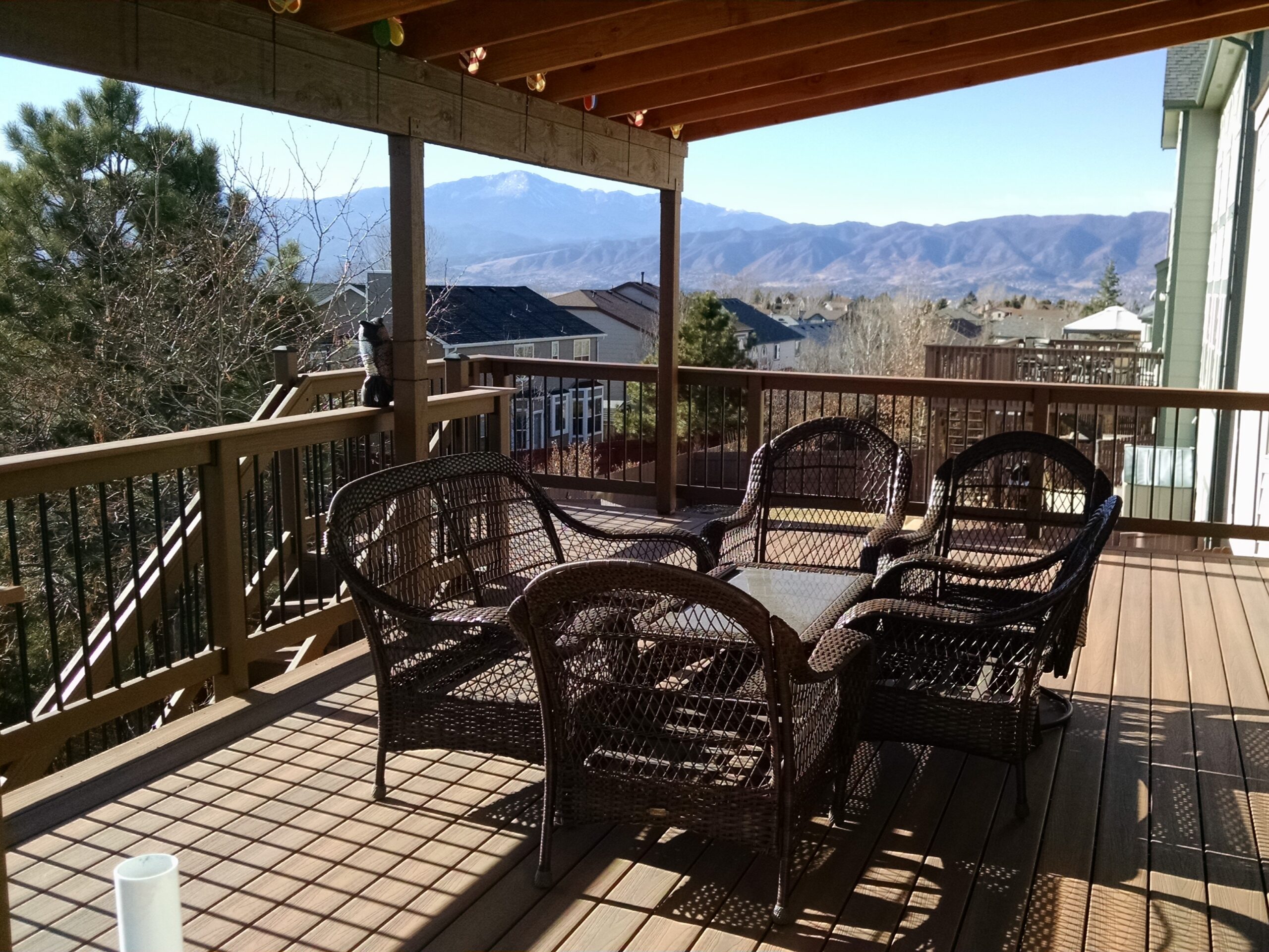 Composite deck in Colorado Springs with steel deck framing, wood and metal deck railing, under-deck drainage system, and shed roof deck cover