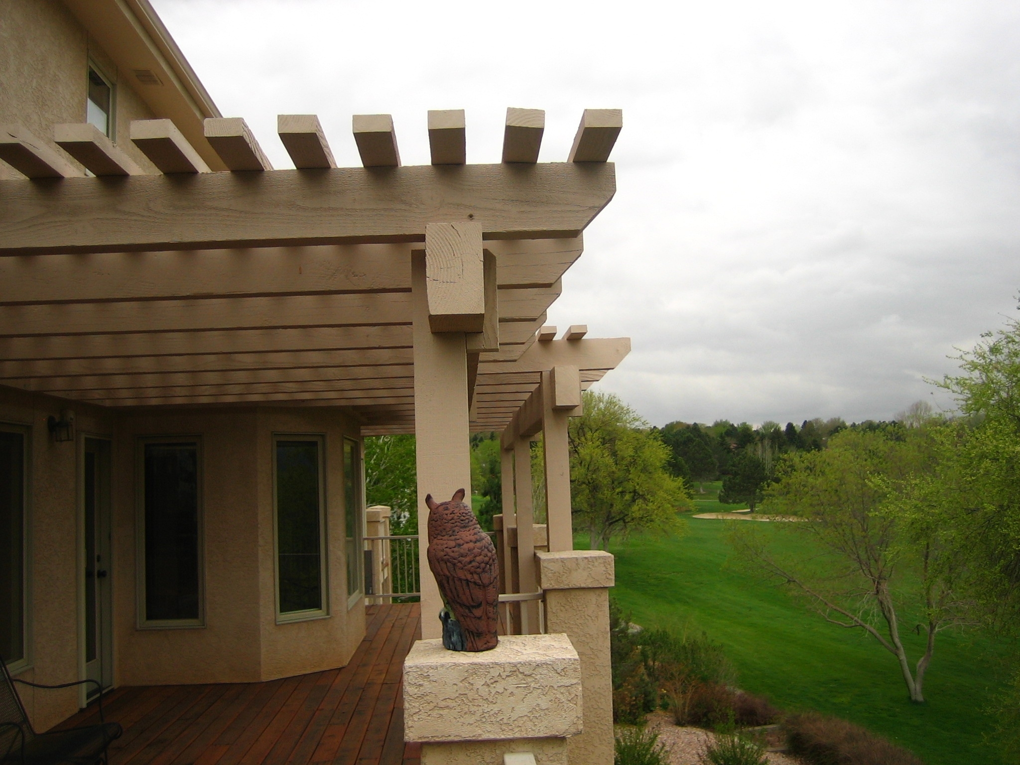 Redwood deck in northeast Colorado Springs featuring a steel deck railing, cedar pergola, glass windbreaks